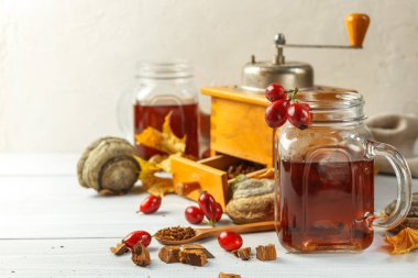 Chaga ve gül suyu karıştırılmış cam kupa. Yakın plan - eski bir kahve öğütücüsü, güllük gülistanlık böğürtlen ve huş ağacı ile