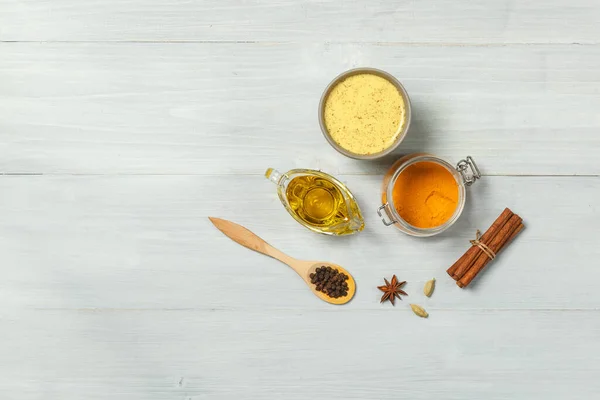 Leche dorada, cúrcuma y especias para cocinar sobre un fondo claro de madera. vista superior con espacio — Foto de Stock