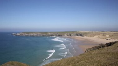Perranporth ve Newquay yakınlarındaki güzel bir günde dalgalar plaj ve sahil ile Holywell Bay Cornwall
