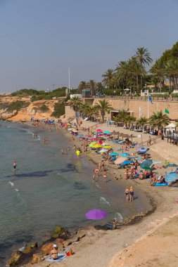 Güzel hava, ziyaretçileri ve tatilcileri Punta Prima, Costa Blanca, İspanya, Pazartesi 1 Temmuz 2019 Pazartesi'de plaja çekti