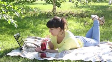 Kız serbest meslek açık havada çalışır. Esmer parkta çim üzerinde oturur ve bir dizüstü bilgisayar ile çalışır. Klavyede internette sosyal ağ üzerinde bir ileti yazdırır.