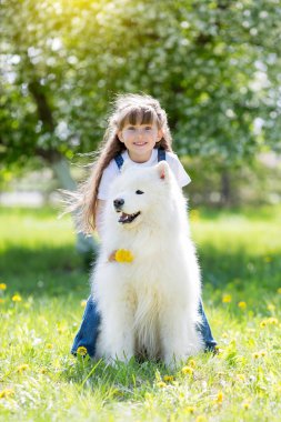 Büyük beyaz bir köpek parkta küçük kız. Güzel bir 5 yıl eski kız Jeans favori köpeğini yaz yürüyüş sırasında hugs..
