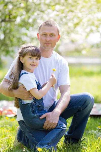 Dad and daughter are sitting together in a city park.