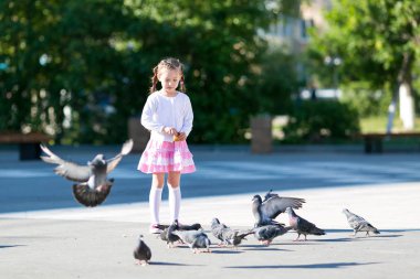 Güzel kız sokak şehir kuşlara ekmek verir. Küçük bir kız güvercin besleme.