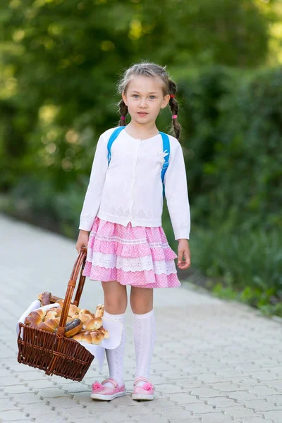 一个小女孩在城里的街上拿着很多面包和饼干 一篮子面包的孩子在路上 — 图库照片