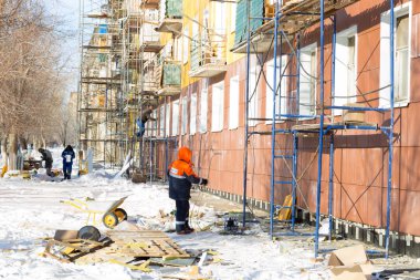 İşçiler ve sıcak cephe bina onarım. Eski ev mineral yün ile sıkıştırılır ve binanın dış kaplı. Sigortası olmayan yükseklikte çalışma