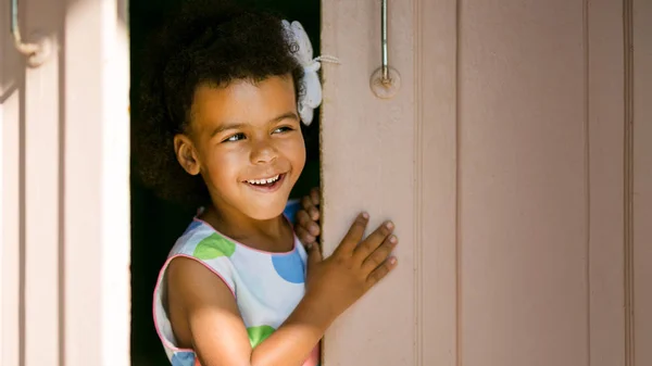 The black girl smiles in the doorway.