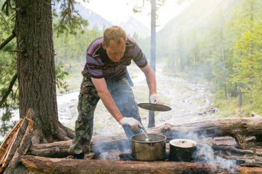 Adam yemek yemek ormandaki tehlikede. Uzun bir yürüyüş içinde bir ksotra üzerinde bir tencerede bir çorba soslu turist müdahale.