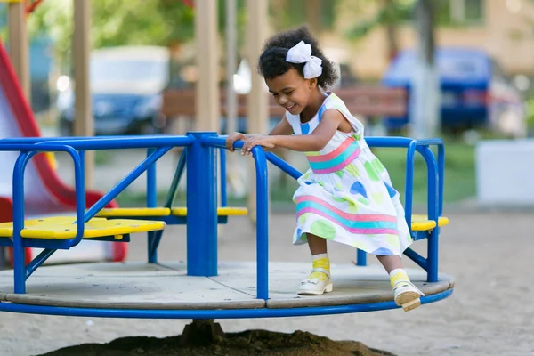 Çocuk evin bahçesinde Bahçesi oynar. Siyah bir kızla bir atlıkarınca at binme.