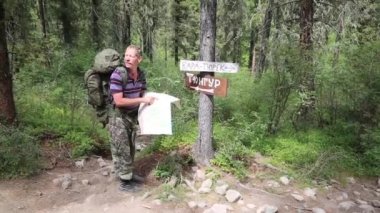 Turist işaretleri yakınındaki bir harita. Yazıtlar tüngür Köyü, Kara Turek dağ. Bir adam gezgin bir zam kayboldum ve harita üzerinde bir yol arıyor.