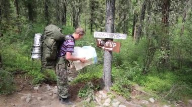 Turist işaretleri yakınındaki bir harita. Yazıtlar tüngür Köyü, Kara Turek dağ. Bir adam gezgin bir zam kayboldum ve harita üzerinde bir yol arıyor.