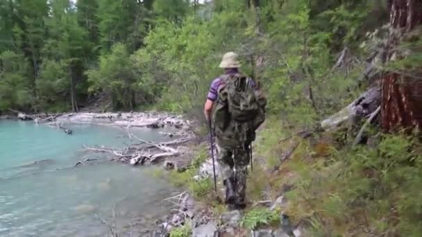 観光客は 湖に沿って歩きます バックパックを持つ男は山の湖近く — ストック動画
