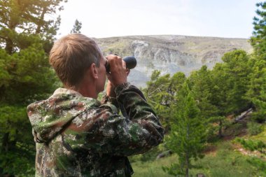 Bir adam bir teleskop dağın tepesine bakar. Turist dürbün dağlara bakar.