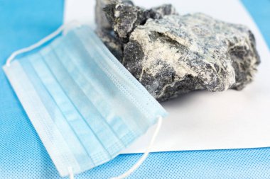 Solunum organları korumak için bir maske kavramı üzerinde zararlı taş asbest madeni yatıyor. Mineral asbest ve solunum koruma maskesi.