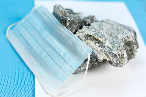 Solunum organları korumak için bir maske kavramı üzerinde zararlı taş asbest madeni yatıyor. Mineral asbest ve solunum koruma maskesi.