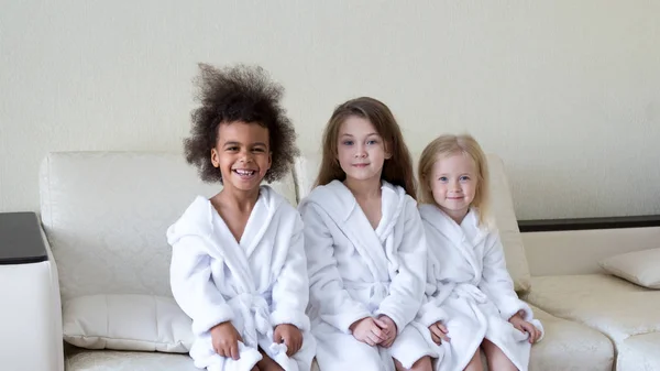 Tres Chicas Diferentes Nacionalidades Están Sentadas Sofá Niñas Con Batas — Foto de Stock