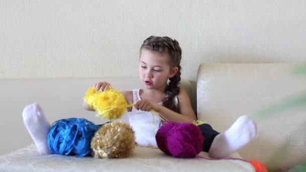 女の子は スレッドを巻きです ソファに座って女の子がボールのように編むことのためのウールを巻きです — ストック動画