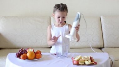 Çocuk bir karıştırıcıda meyve parçaları koyar. Kız dilimlenmiş elma ve armut suyu ve bir kokteyl yapmak için bir karıştırıcıda koyar.