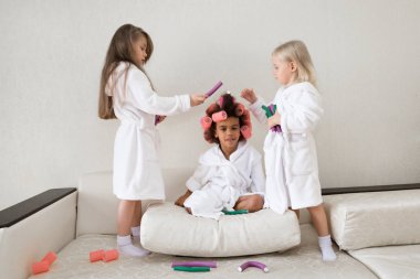 Siyah kız rüzgar curlers saçında. Küçük kızlar saç curlers ve saç tokaları ile oynamak.