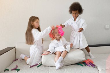 Küçük kızlar saç curlers ve saç tokaları ile oynamak. Kızlar kız beyaz kat olarak curlers örgü ve saç her drg saçında küçük resimleri.
