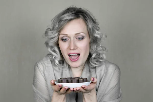 Uma mulher loira com um prato de chocolates . — Fotografia de Stock