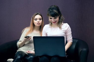 Kız arkadaşları Internet cihazları ile birbirlerine baktılar gözetleme izliyor. Telefon ve kız kanepede bir dizüstü bilgisayar ile kız.