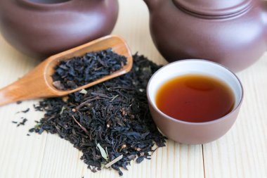 Çay ve siyah çay tabakları masaya serpilir. Çay töreni kümesi ve ahşap arka plan üzerinde siyah aromalı çay