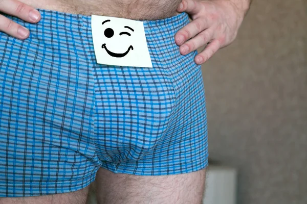 Sheet of paper with a cheerful face on men's shorts. — Stock Photo, Image