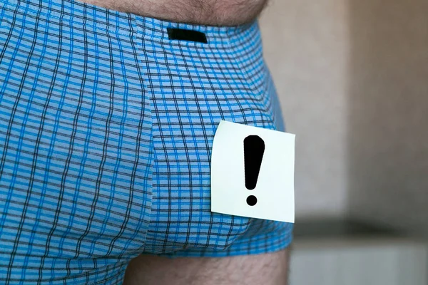 Paper sheet sticker with exclamation mark on men\'s underwear. Paper exclamation mark on men\'s shorts.