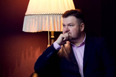 Kanepede oturan bir ceketli bir sakallı sağlam adam