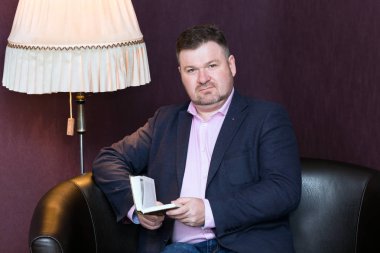 Bir adam elinde bir kitapla kanepede oturuyor.