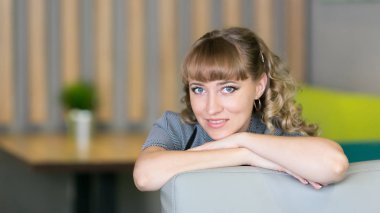 Gri elbiseli bir genç bir kadın trendy bir kafede oturuyor. Güzel seksi kadın 30 yaşında.