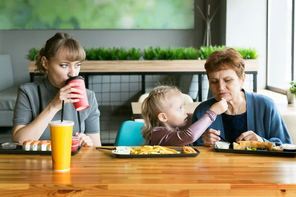 Grandmother, daughter, granddaughter eat in a cafe. Family dinner generation of women.