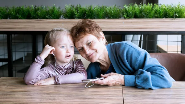 Abuela llevaba auriculares a su nieta para escuchar el cuento de audio . — Foto de Stock