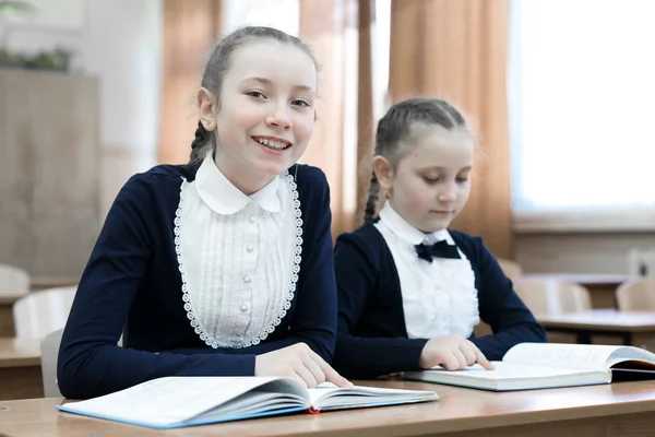 I bambini scrivono mentre sono seduti alla scrivania della scuola . — Foto Stock