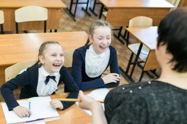 Kız öğrenciler öğretmenlerine gülerler. İki kız kız öğrenci öğretmenlerine bir derse gülüyor