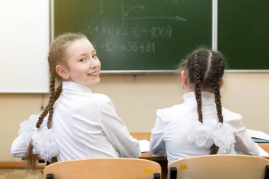 Kız öğrenci geriye bakıyor. Bir kız öğrenci genç geriye baktı ve okulda sınıf arkadaşı gülümsüyor.