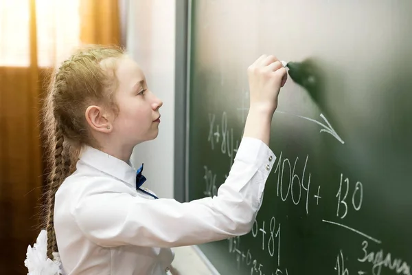 Een vrouwelijke basisschool student schrijft op het Blackboard. — Stockfoto