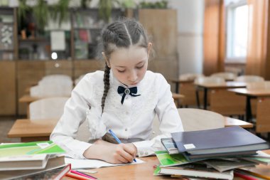 Başarılı bir kız öğrenci ödevini yapan mükemmel bir öğrencidir. Güzel bir duruş ince ile güzel kız öğrenci genç, bir sınıfta oturan, bir not defterine yazılmış bir görev yapıyor.