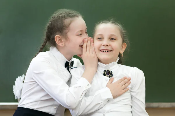 Kız öğrenci sınıf arkadaşları ofiste ki tahtanın yanında kulağına fısıldayan sırları paylaşıyorlar..