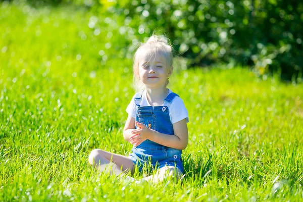 소녀가 잔디위의 공원에서 스포츠와 명상에 종사하는 포즈를 취하고 있습니다 — 스톡 사진