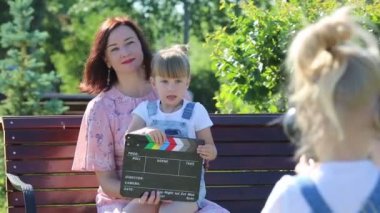 Kameralı kulaklıklı küçük bir kız olay örgüsü çekiyor. Çocuk blogger internet çocuklar üzerinde kendi kanalında anne ve kız kardeşi vuruyor bir video hikaye hazırlamak, sosyal ağlar için haber