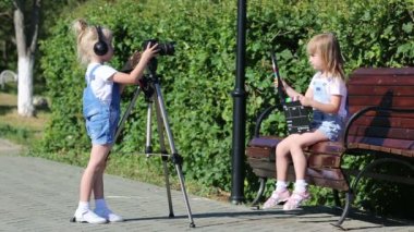 Bir şehir parkında fotoğraf appart ile çocuklar. 4-5 yaşındaki kızlar bir fotoğraf makinesinde video çekiyor, televizyon çalışanlarını oynuyorlar..