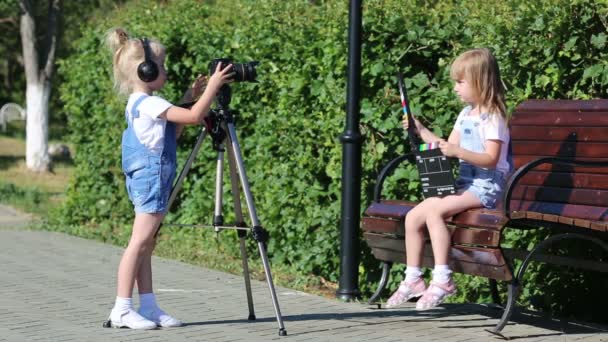 市内の公園で写真のアパルトを持つ子供たち 5歳の女の子が写真機でビデオを撮影し テレビの労働者を演じている — ストック動画
