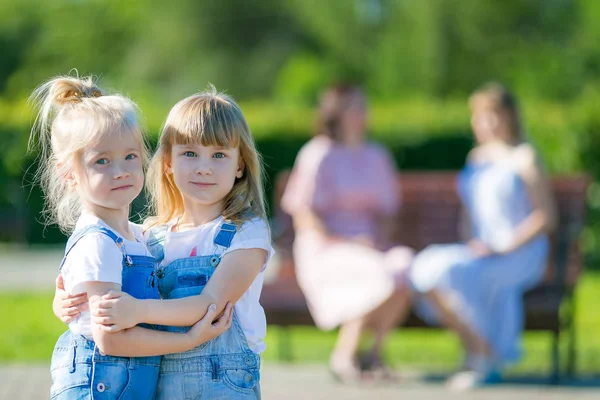 Zwei Mädchen wurden Freunde und umarmten sich, während ihre Mütter sprachen. — Stockfoto