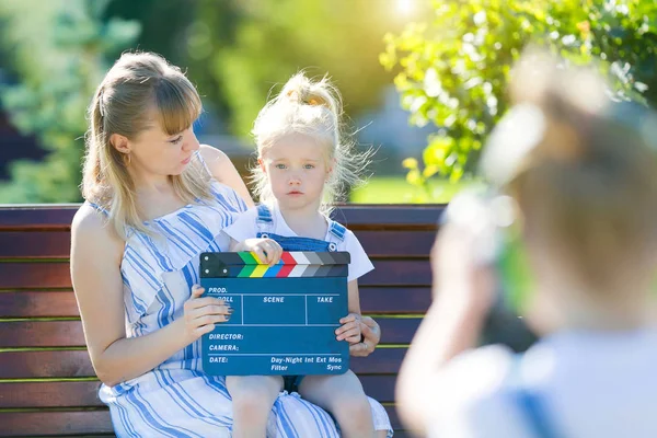 En liten flicka i hörlurar med en kamera skjuter tomten. — Stockfoto