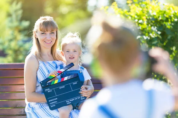 En liten flicka i hörlurar med en kamera skjuter tomten. — Stockfoto