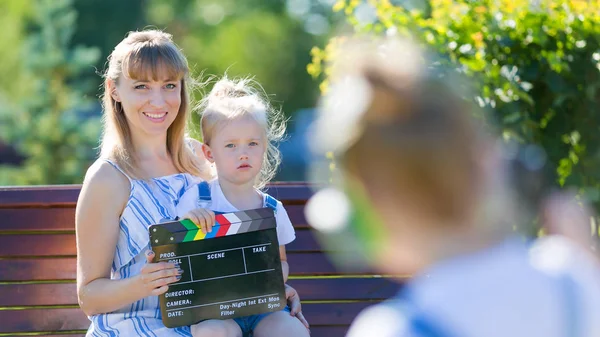 En liten flicka i hörlurar med en kamera skjuter tomten. — Stockfoto