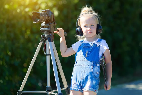 Child novice video blogger with a camera and a tripod.