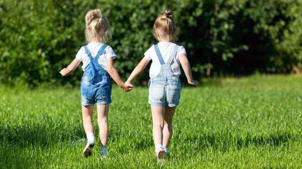 Gyermekek futnak a zöld fű kezében kezében. — Stock Fotó